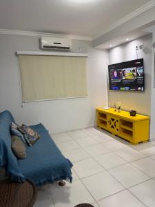 een woonkamer met een gele tafel en een tv bij Mariscal 2 quartos 3 banheiros -SOBRADO AMENDOEIRA in Bombinhas