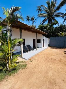 a white building with palm trees in front of it at Coconut Tree hill Rekawa in Tangalle