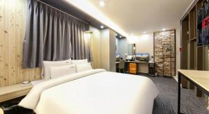 a bedroom with a large white bed and a desk at Hotel Haeseong in Changwon
