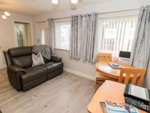 a living room with a leather couch and a table at Primrose Cottage in Chathill