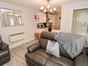 a living room with a couch and a kitchen at Primrose Cottage in Chathill