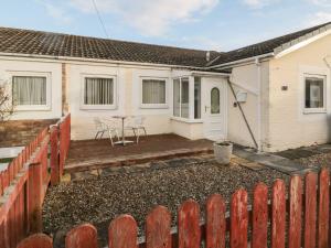 a house with a wooden fence in front of it at Primrose Cottage in Chathill