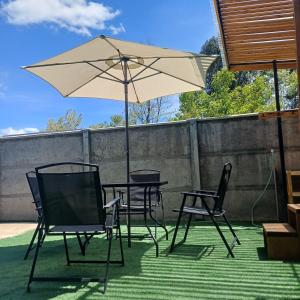 a table and chairs and an umbrella on a patio at Refugio las Mariposas Chillán in Chillán