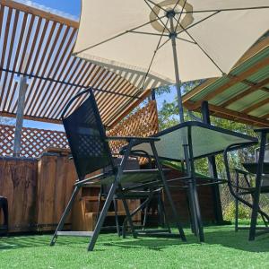 een paar stoelen en een parasol op een gazon bij Refugio las Mariposas Chillán in Chillán