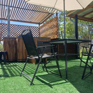 een tafel en stoelen onder een paraplu bij Refugio las Mariposas Chillán in Chillán