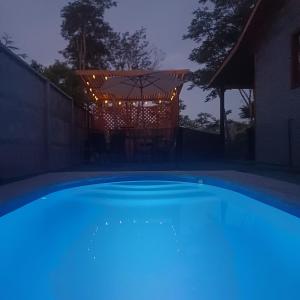 a large blue swimming pool with an umbrella at night at Refugio las Mariposas Chillán in Chillán