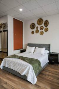 a bedroom with a large bed with plates on the wall at Golden Hour @TheMillRowsSuites in New Glasgow