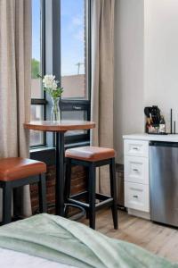 a table and two stools in a room with a window at The Classic @TheMillRowsSuites in New Glasgow