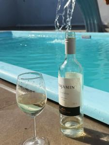 a bottle of wine and a glass next to a swimming pool at Espaço massagueira in Marechal Deodoro
