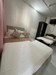 una camera con 2 letti con lenzuola e cuscini bianchi di SGH Mathilu Rodadero a Santa Marta