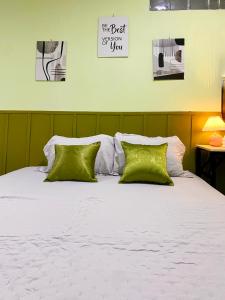 a bed with two green pillows on top of it at Bandung CoStay in Bandung