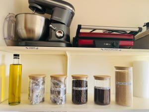 a shelf with five jars of spices and a mixer at 360onSea in De Kelders