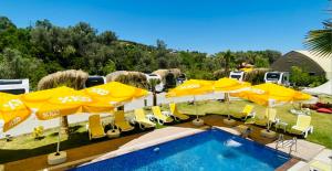 a group of yellow umbrellas and chairs next to a pool at Güneş' te Karavan Otel in Karaburun