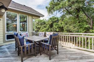 eine Holzterrasse mit einem Tisch und Stühlen auf einem Haus in der Unterkunft 3050 - Whispering Pines in Southern Shores