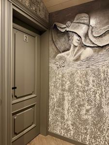 a wall mural of a woman wearing a hat at Insula Poilsio Namai in Telšiai