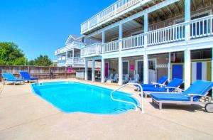 een zwembad met blauwe stoelen en een gebouw bij 1676 - Good Humor in Corolla