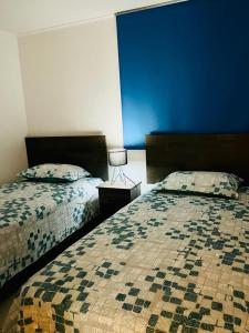 een slaapkamer met 2 bedden en een blauwe muur bij Apartment with a private backyard in Los Molles