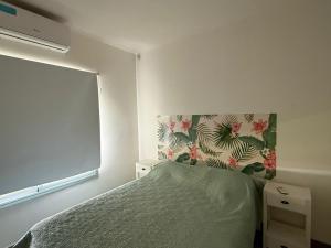 ein Schlafzimmer mit einem Bett mit einer grünen Bettdecke und einem Fenster in der Unterkunft La casita de Isa in Gualeguay + 19 Fotos