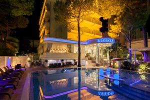 a swimming pool in front of a hotel at night at Hotel Alexander in Milano Marittima