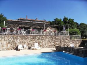 a swimming pool with two chairs and a stone wall at Le Mas de la Grenouillère in Joyeuse
