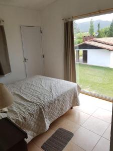 een slaapkamer met een bed en een groot raam bij Casa Punilla in Valle Hermoso