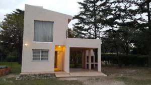 een wit huis met een deur in een tuin bij Casa Punilla in Valle Hermoso