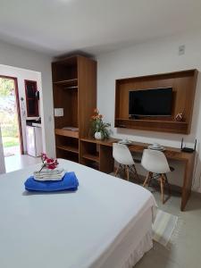 een slaapkamer met een bed, een bureau en een televisie bij Pousada Jeito Bom de Viver in Caraíva