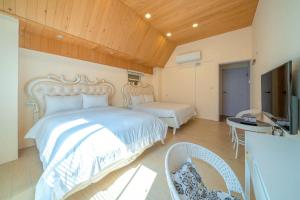 een slaapkamer met een wit bed en een televisie bij 騎馬打仗民宿 in Yilan +32 foto's