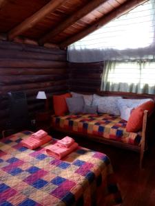 a bedroom with two beds in a log cabin at Cabaña Alcione in Capilla del Monte
