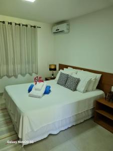 een slaapkamer met een groot wit bed met kussens bij Pousada Jeito Bom de Viver in Caraíva