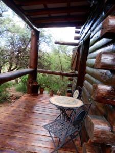 a wooden deck with a table and a chair on it at Cabaña Alcione in Capilla del Monte