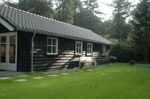 a log cabin with a lawn in front of it at Aan de Bosrand Hoenderloo in Hoenderloo