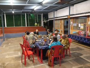 eine Gruppe von Menschen, die an einem Tisch in einem Restaurant sitzen in der Unterkunft Shantadurga Beachside Homestay in Guhagar