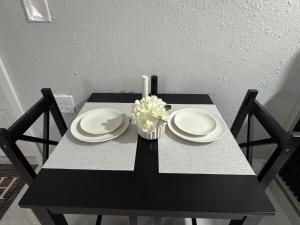 een zwarte tafel met twee borden en een vaas met bloemen bij Private Studio with Patio-King Bed, Near Beach & Casinos in Hollywood
