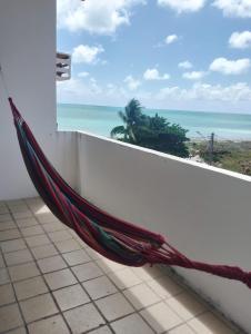a hammock on a balcony with a view of the ocean at Apartamento BEIRA MAR - Edifício Mar Del Plata in Itamaracá