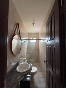 een badkamer met een wastafel, een toilet en een spiegel bij Franz Beach in Nova Viçosa