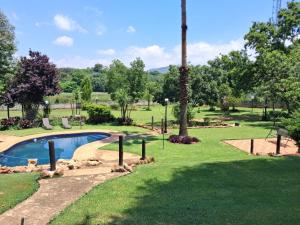 a swimming pool in a park with a palm tree at Greenstone Guesthouse in Muldersdrift