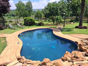 a swimming pool with a brick pathway around it at Greenstone Guesthouse in Muldersdrift