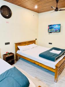 a bedroom with two beds and a tv on the wall at Sanju Homestay in Chikmagalūr