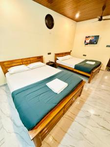 two twin beds in a room with a clock on the wall at Sanju Homestay in Chikmagalūr