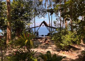 une table de pique-nique dans une forêt avec l'océan en arrière-plan dans l'établissement Pyramid Yoga Koh Phangan, à Ko Pha Ngan