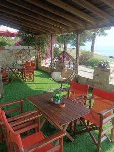 patio con sedie, tavolo in legno e altalene di Lia Apartment Sea View a Nea Fokea
