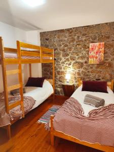 une chambre avec deux lits superposés et un mur en pierre dans l'établissement casa na aldeia - entre Fundão e Covilhã, à Pêro Viseu