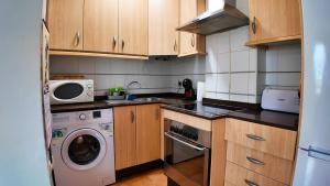 eine kleine Küche mit Holzschränken und einer Waschmaschine und einem Trockner in der Unterkunft Apartalux Vera Palace in Vera
