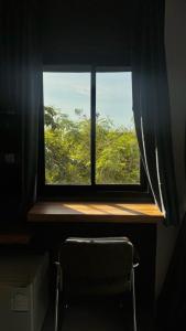 een raam met een stoel en uitzicht op een boom bij Kefir Phuket in Kamala Beach
