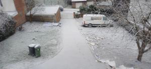 een met sneeuw bedekte oprit met een vuilnisbak en een busje bij Belle CHAMBRE in Seraing