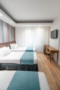 布宜诺斯艾利斯Dorá Hotel Buenos Aires的一间酒店房间，里面有两张床和一张桌子。