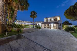 una casa con un vialetto e palme di notte di Villa Mare Salento a Taurisano