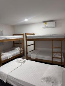 een kamer met 3 stapelbedden met witte lakens bij Hostal Cilipo in Palomino