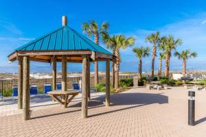 a picnic shelter with a bench and palm trees at Phoenix East 002 in Orange Beach